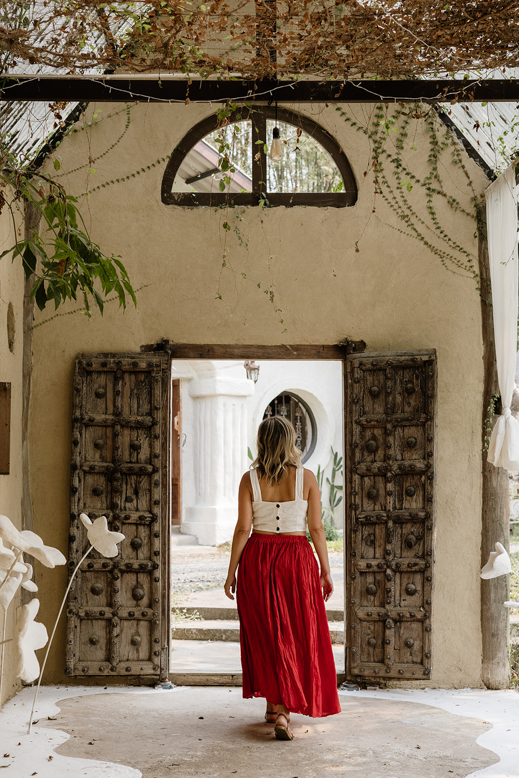 A woman stepping through open wooden doors into light
